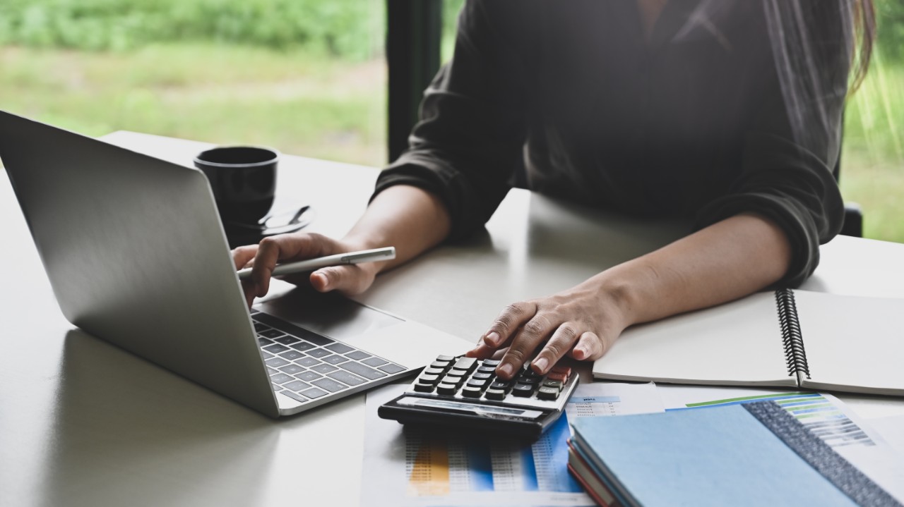 Businessperson working on a laptop and calculator.