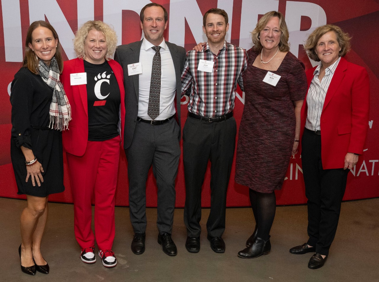 Men and women in red and black professional dress pose for a picture.