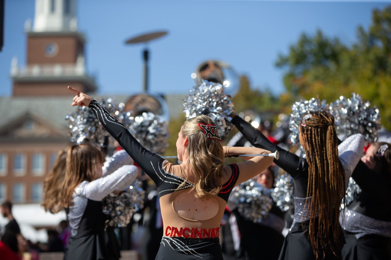 Cheerleaders in parade with UC building in background