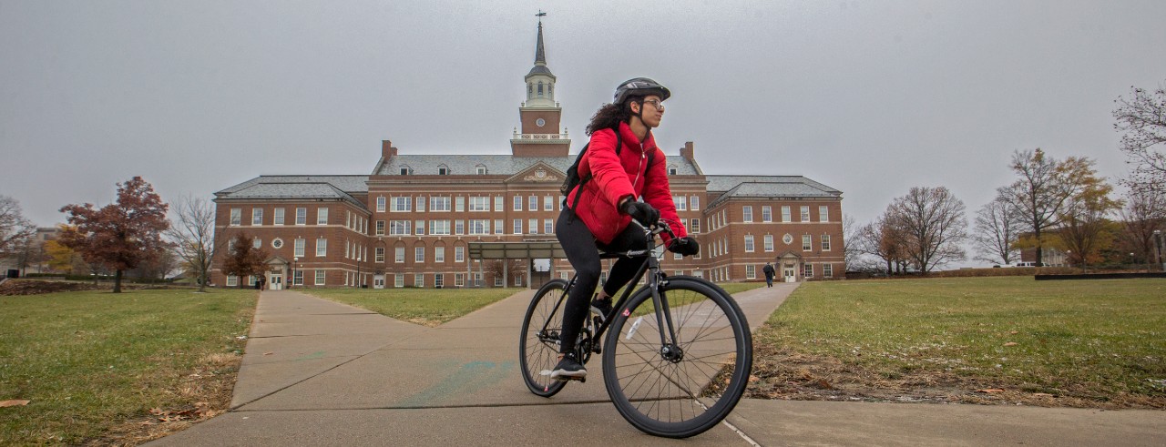 A bicyclist pedals in front of Arts and Sciences Hall.