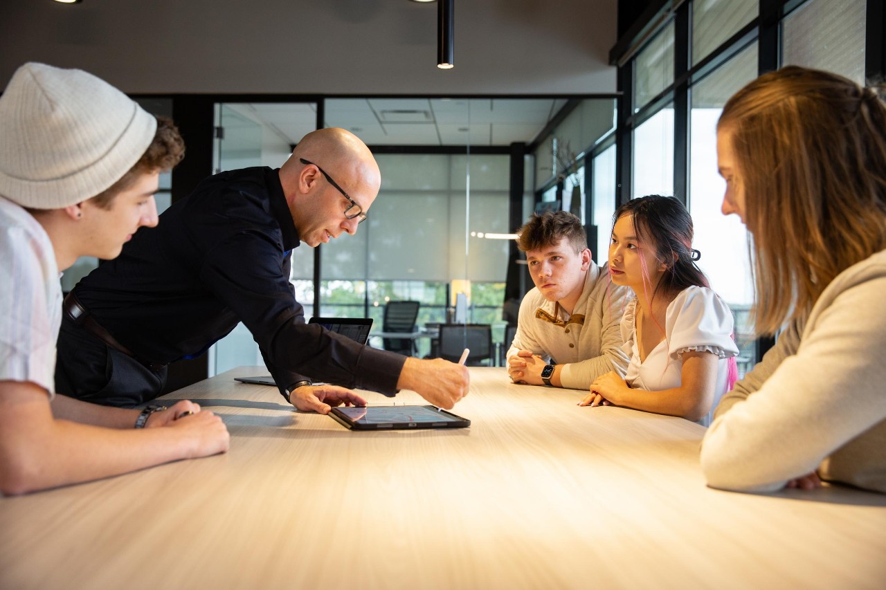 UC interns and co-op students meet with an employer at a large conference table