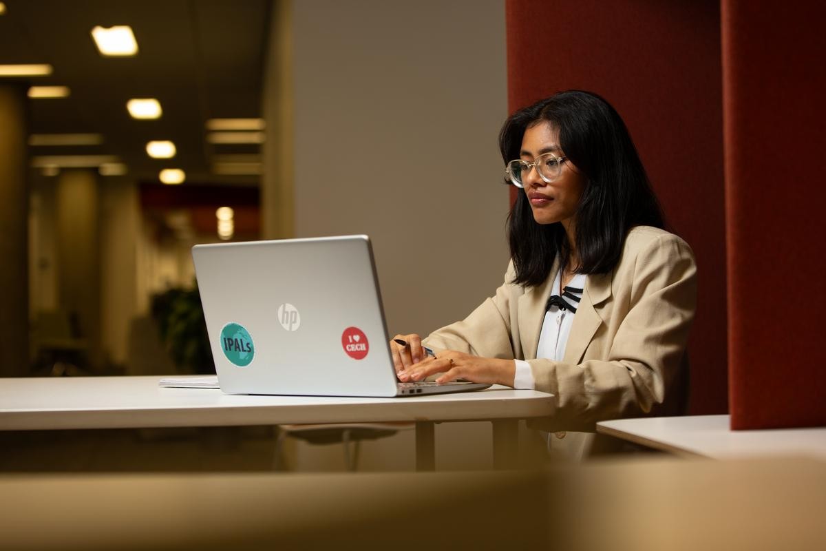 A graduate school student types on their computer in Langsam Library