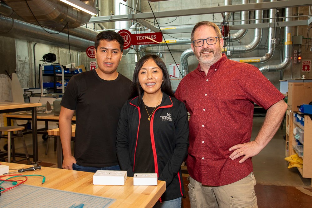 two students and professor posing in science lab