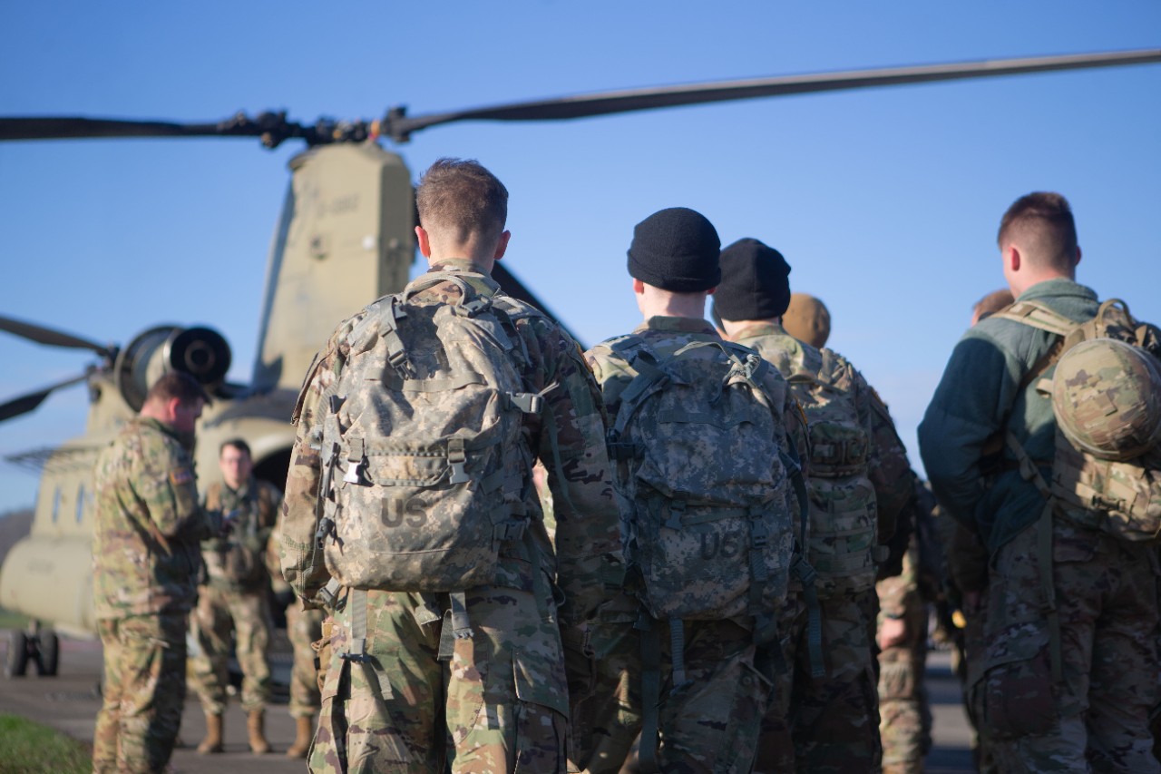 Military members stand near a helicopter