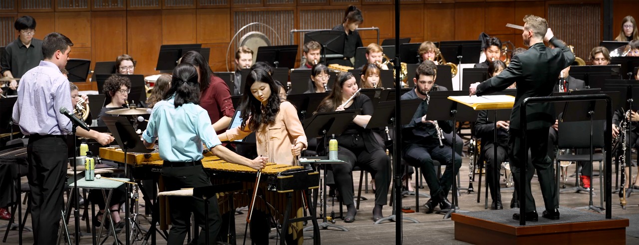 The CCM Wind Symphony performs on stage with a percussion quartet in Corbett Auditorium. Photo taken from the video recording of CCM's performance on Nov. 1, 2024.