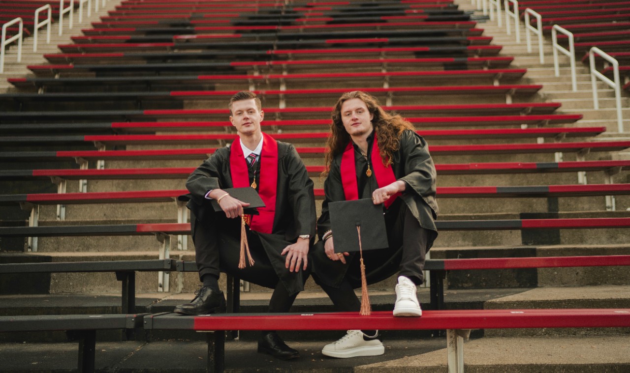 Bowen and Finn Alexy pose for a photo in bleacher seats after graduating from the University of Cincinnati.