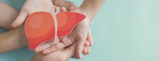 Overlapping hands of multiple people hold an illustration of a liver