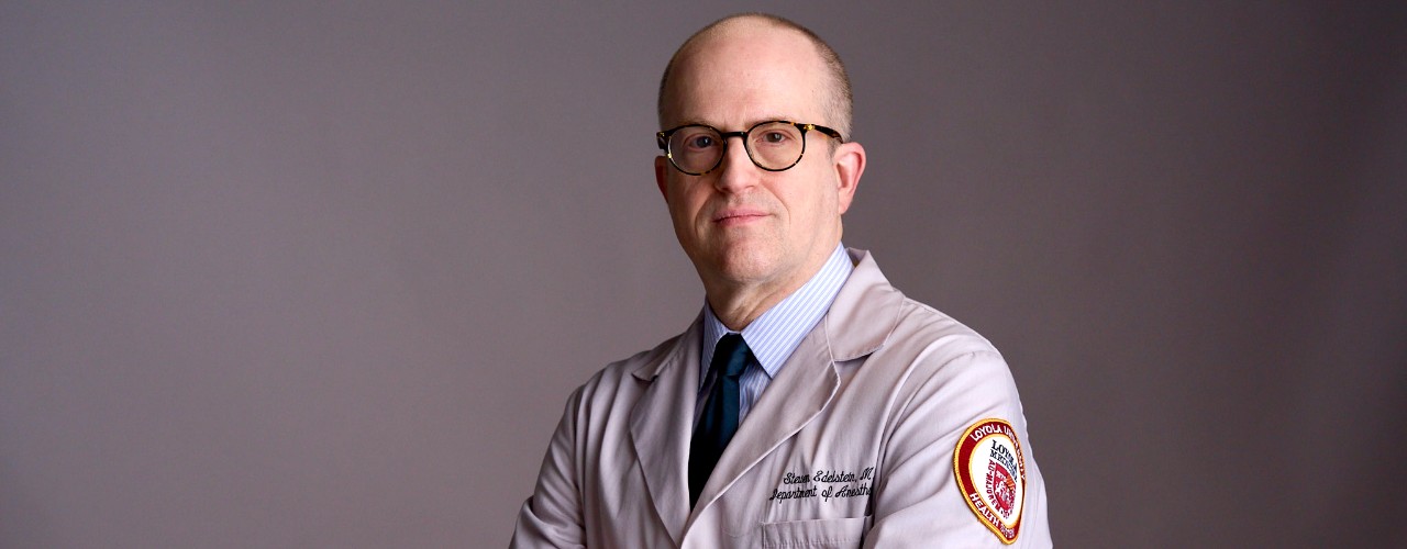 Portrait pose of UC alum Dr. Steven Edelstein facing forward wearing a white medical coat from Loyola University Medical Center.