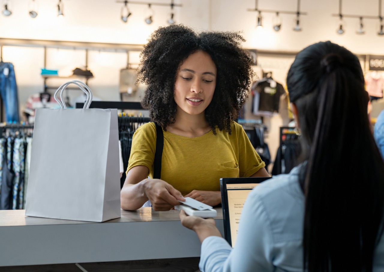 woman shows her credit card while making a purchase at a clothing store