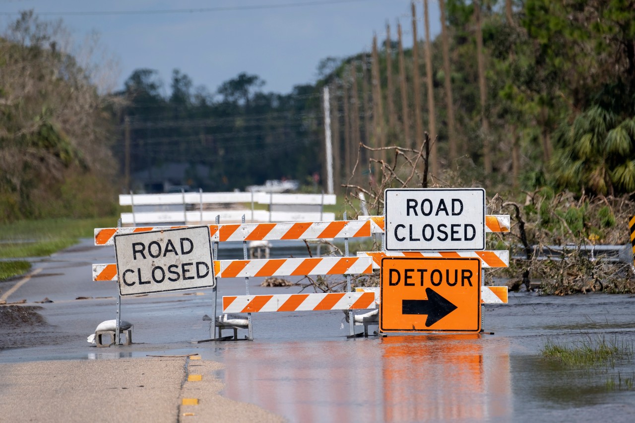 Road closed signs block a flooded road.