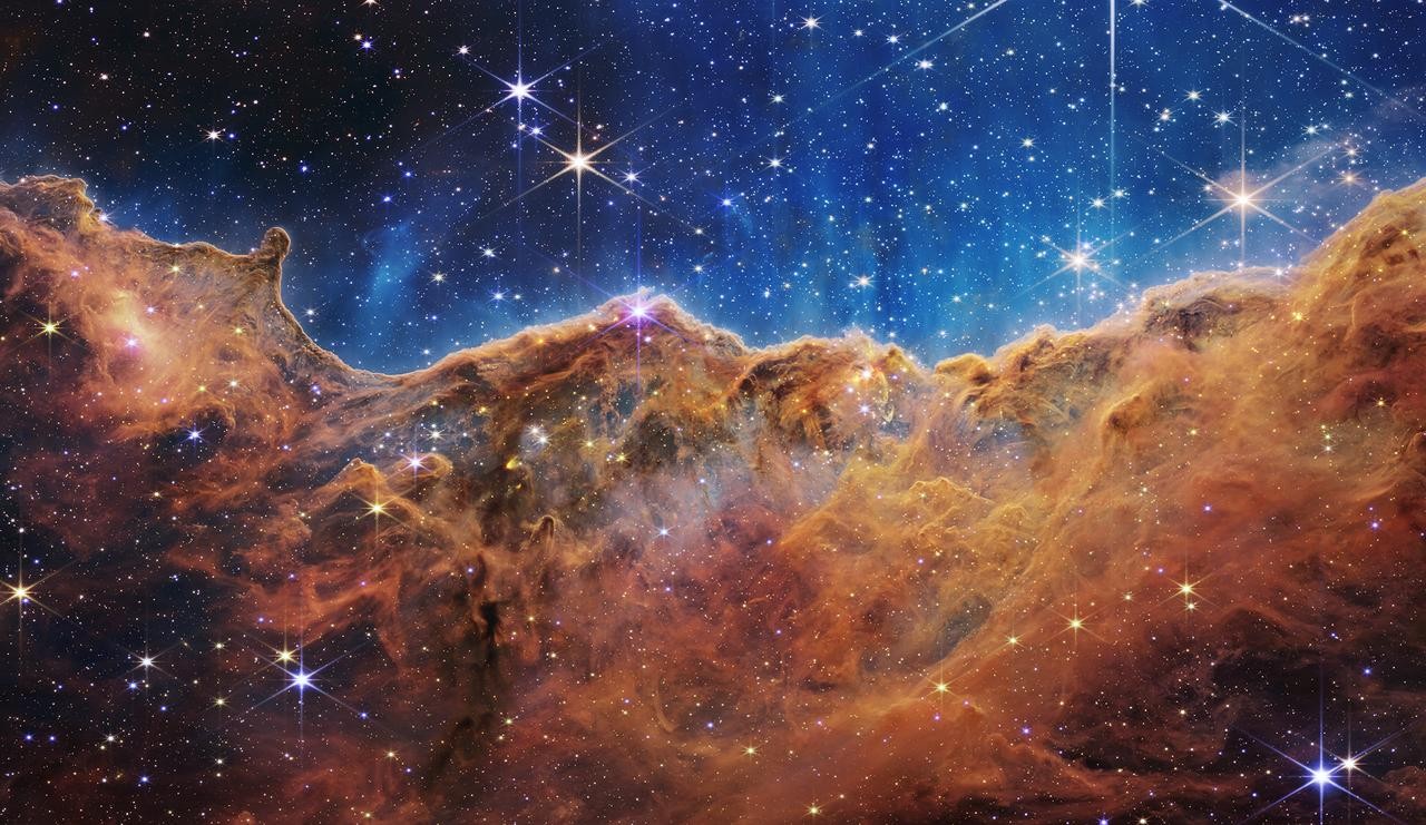 The colorful cloud-like formations and stars of the Carina Nebula against a deep-blue backdrop of space.