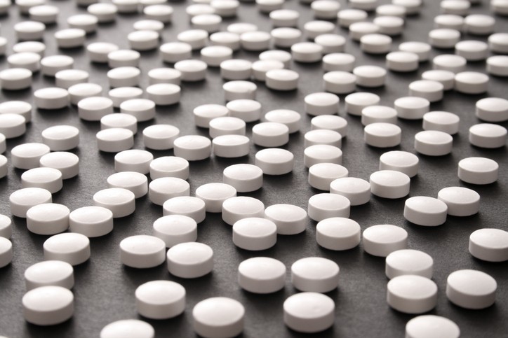 Many white round pills on a black counter