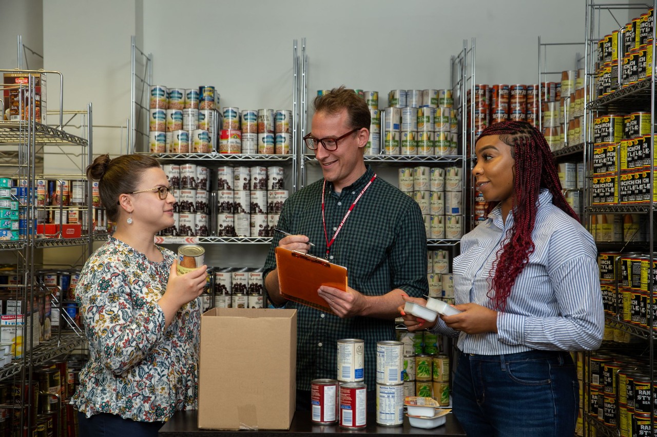 three people shown at the Bearcat Pantry speaking amidst aisles of food