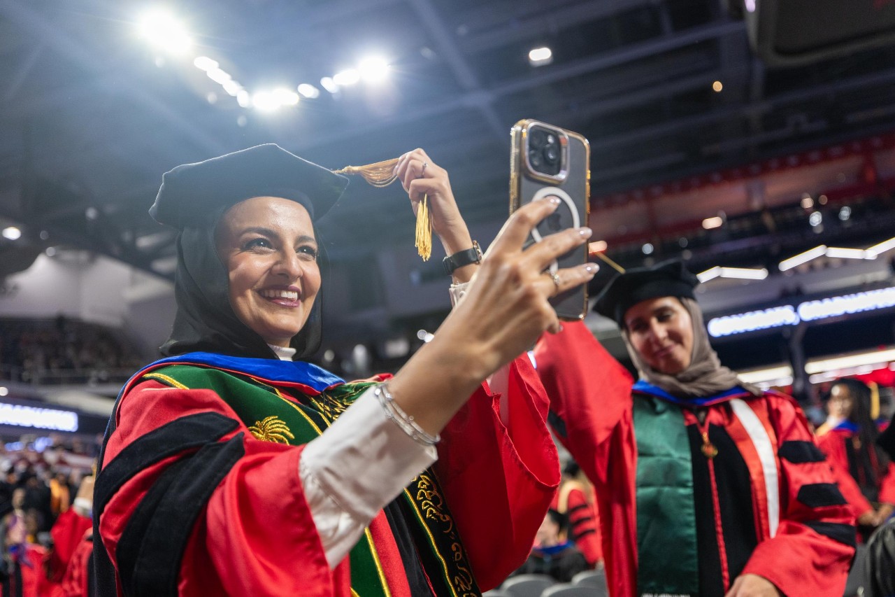 A UC grad takes a selfie while turning her tassel at Fifth Third Arena.