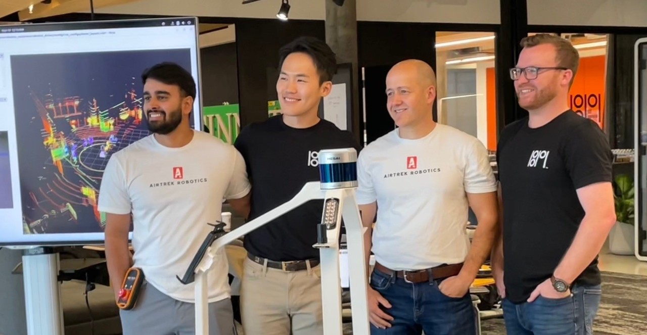 Four men stand behind a robot.