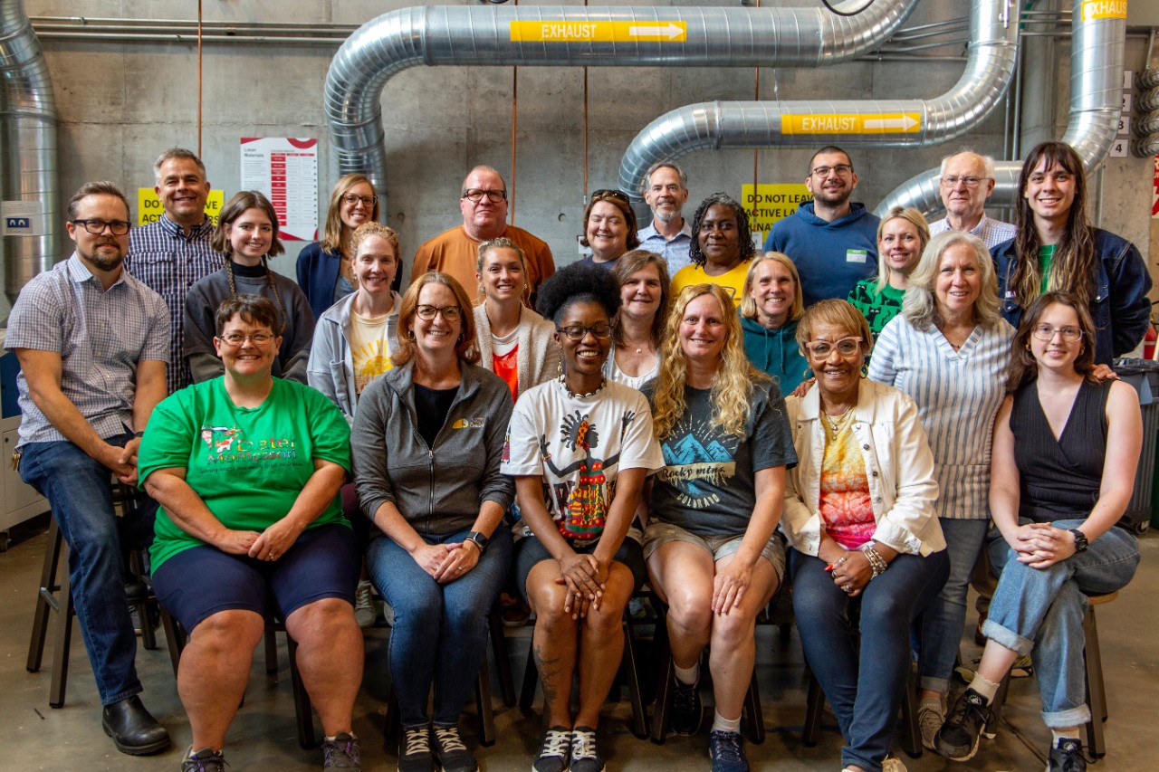 A group of people in the 2024 Makers in Education class pose for a photo in 1819 Ground Floor Makerspace.