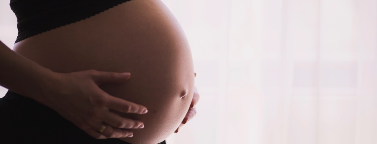 A pregnant woman's hands on her bare stomach