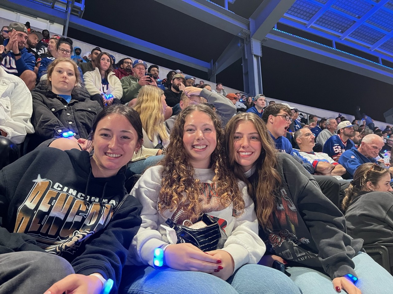 three young women shown in a stadium at baseball game in New York City