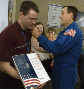 Astronaut Richard R. Arnold II gives Robert Polsgrove his Silver Snoopy pin.