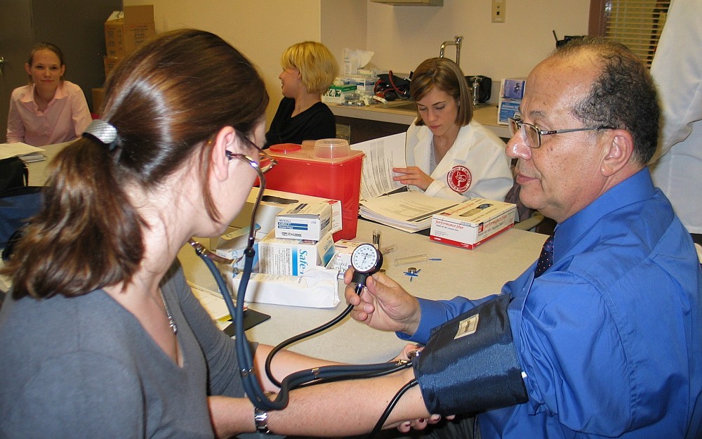 Adel Sakr, PhD, (right), helps a student learn the proper way to take a patient's blood pressure.