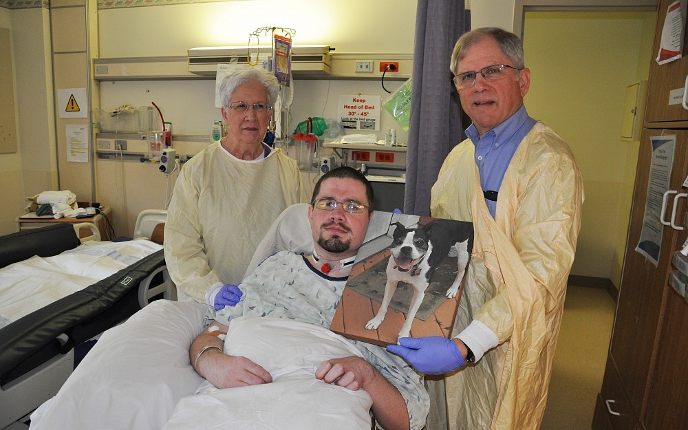 Andrew Reesey, a UCNI patient, pictured with his parents and a photo of his dog